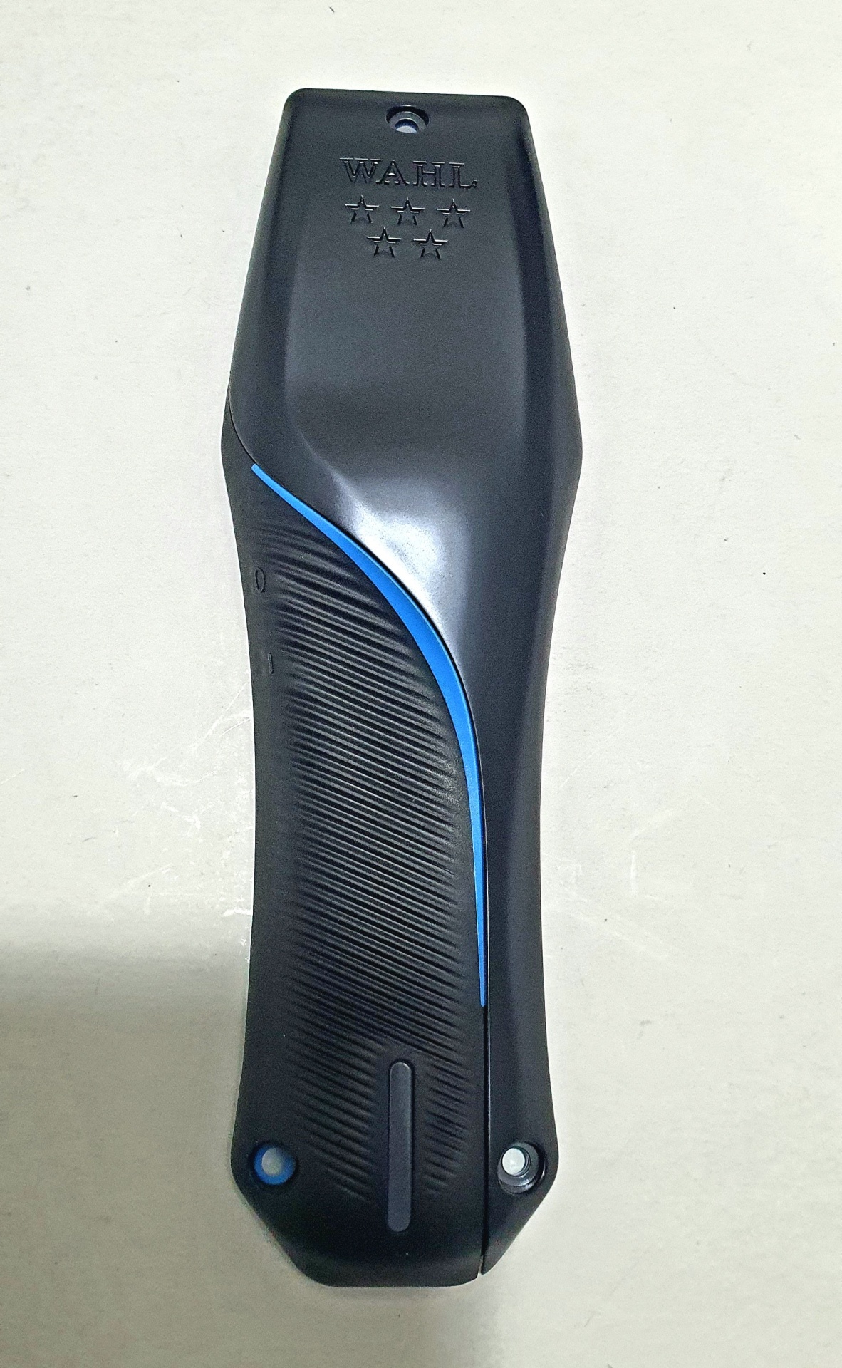 Parte traseira de aparelho elétrico preto com faixa azul e texto em relevo WAHL