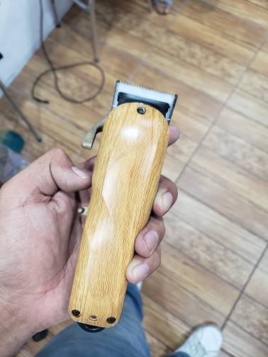 Máquina de cortar cabelo com corpo em madeira clara e lâmina metálica