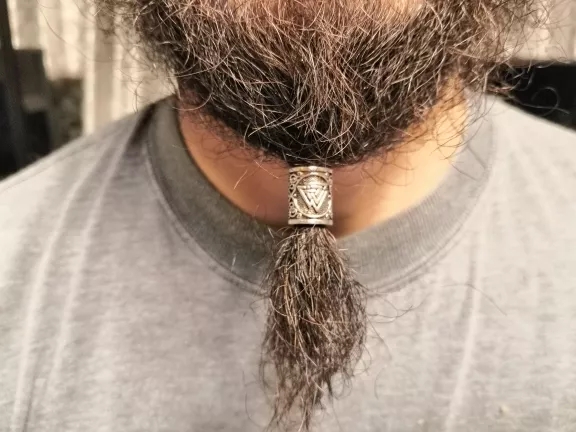 Barba castanha espessa presa com clipe decorativo prateado sobre t-shirt cinza