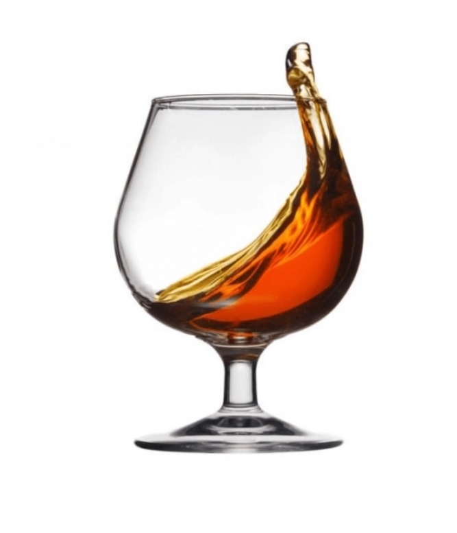 Copo de vidro com líquido âmbar em movimento