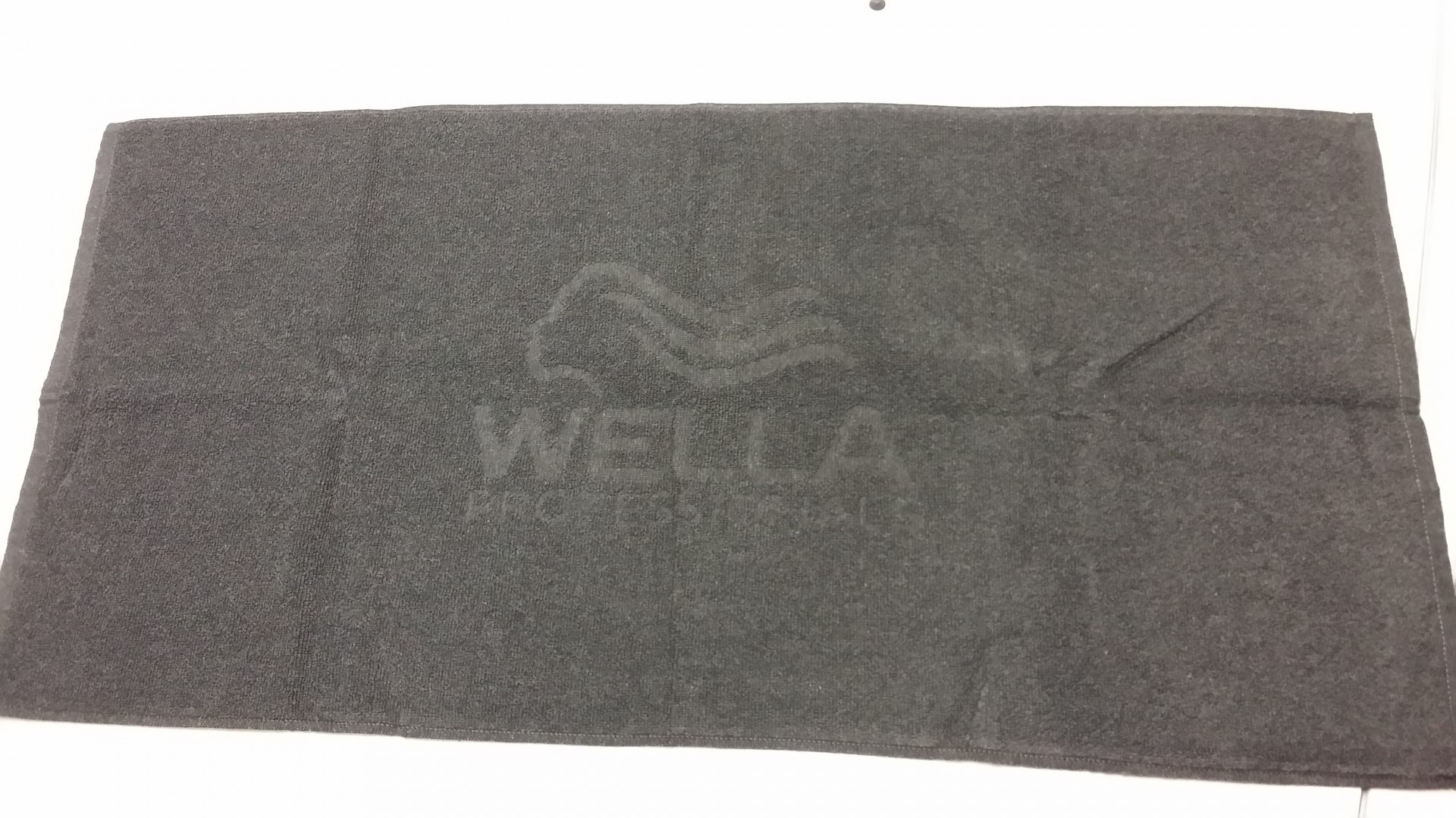 Toalha cinzenta com logótipo WELLA PROFESSIONALS