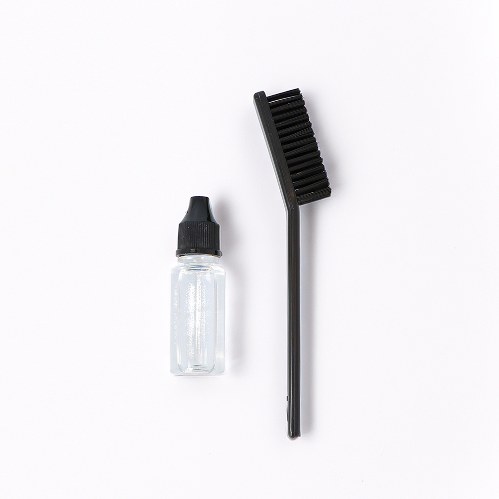 Escova preta e frasco transparente com tampa preta sobre fundo branco