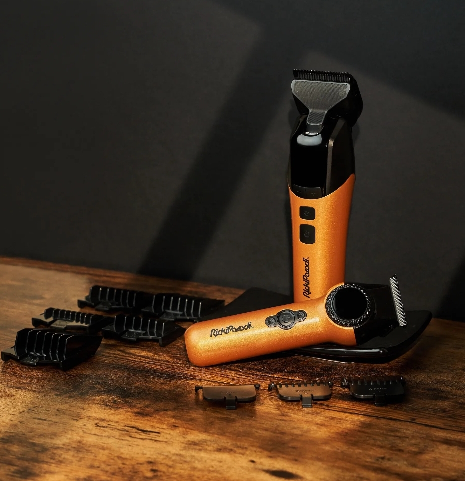 Máquinas de barbear laranja e preto com pentes ajustáveis sobre madeira escura