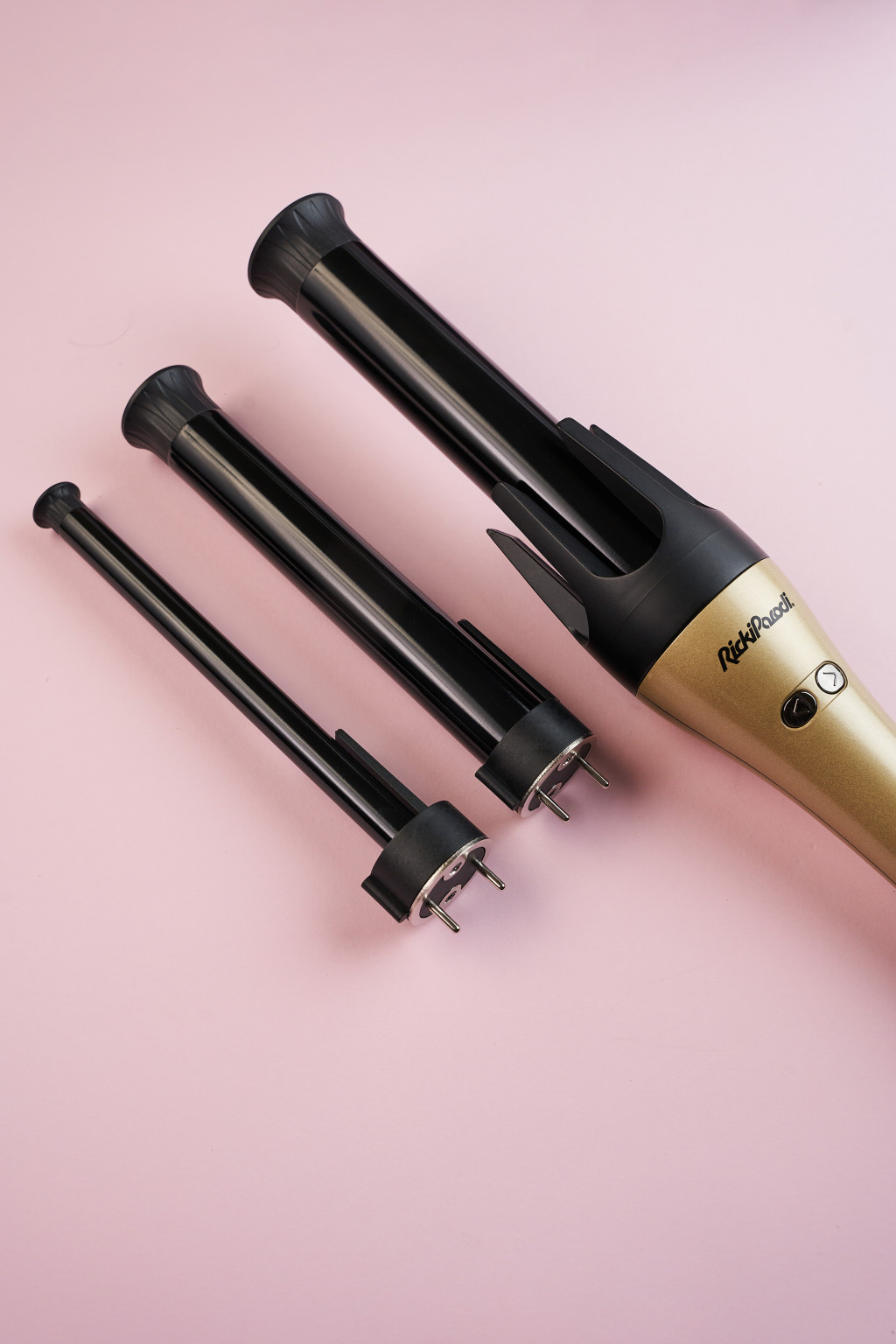 Modelador de cabelo dourado RideRoad com três extensões pretas em fundo cor-de-rosa