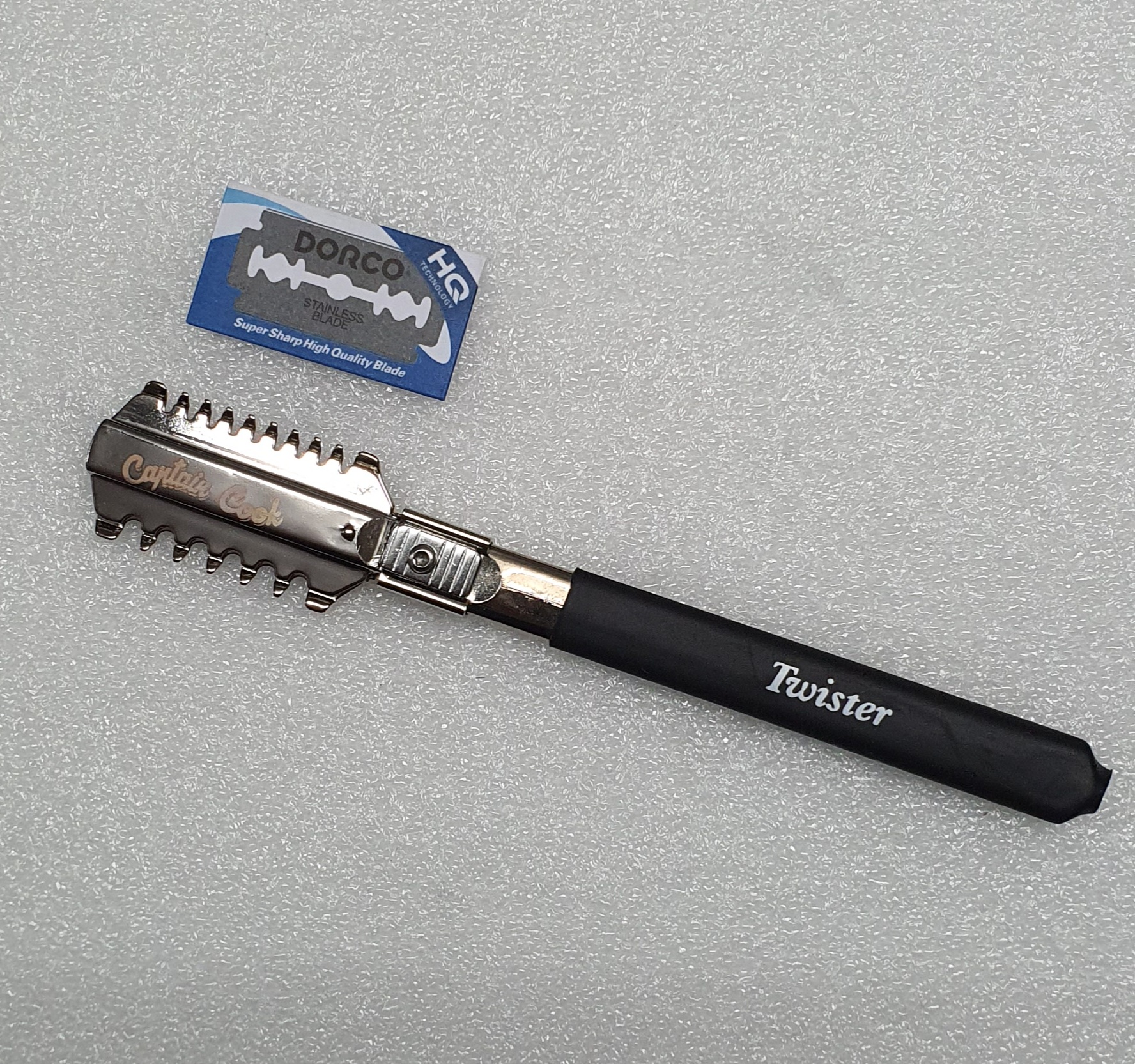 Navalha de barbear com cabo preto e lâmina metálica, ao lado lâmina de barbear DORCO HD