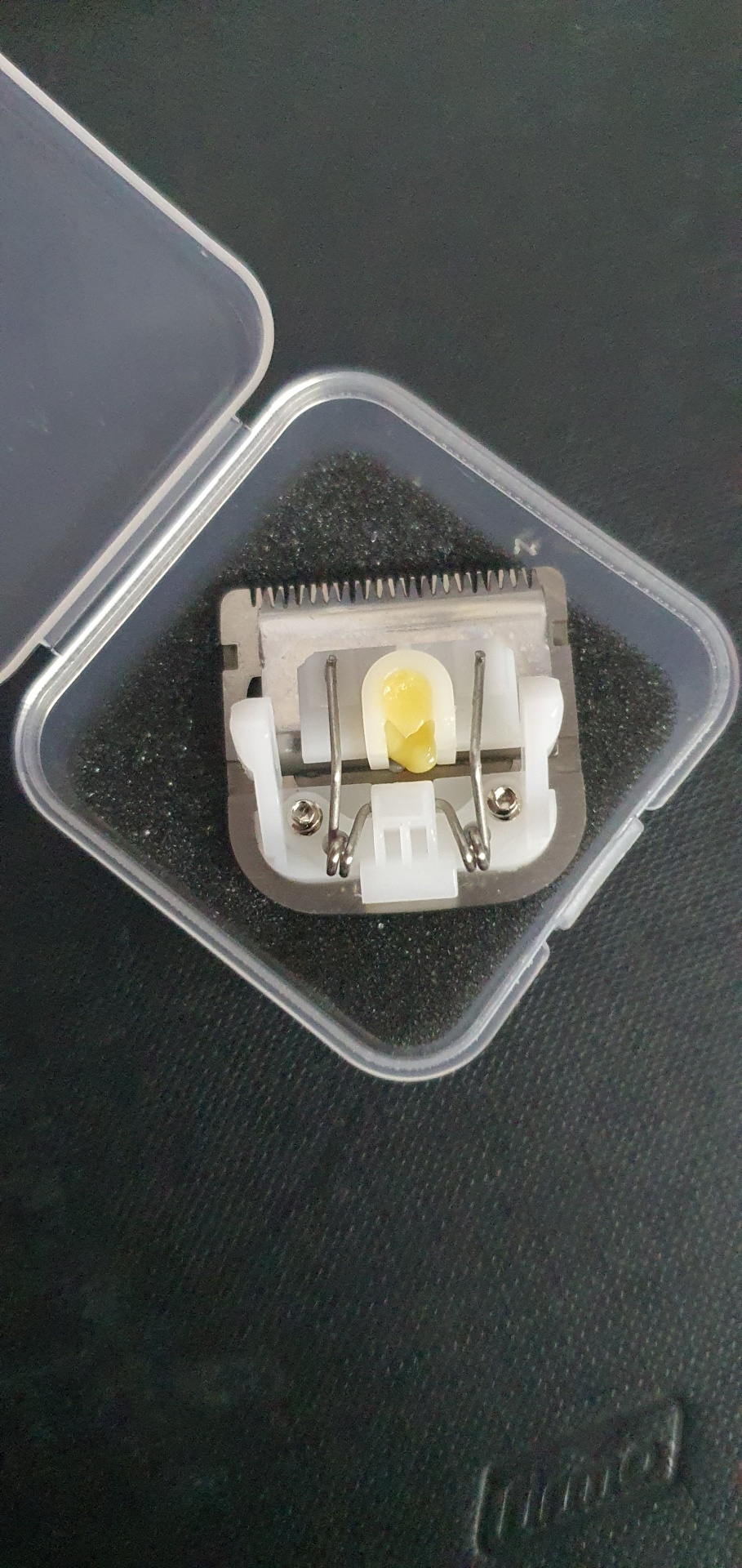 Lâmina de cortar cabelo com peça plástica num estojo transparente