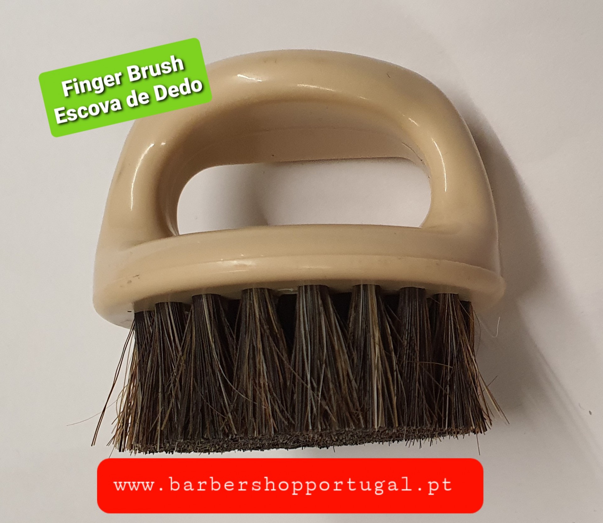 Escova de dedo com cabo bege e cerdas escuras sobre fundo branco