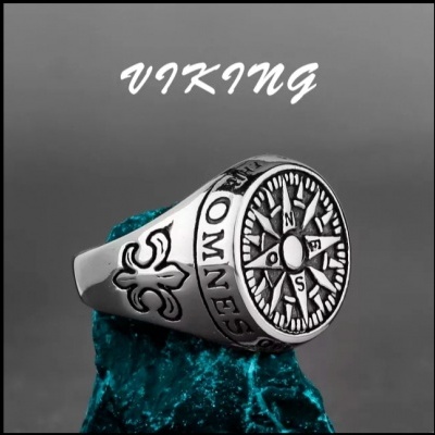 Anel prateado com bússola e símbolos, sobre pedra azul