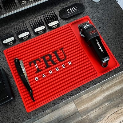 Ferramentas de barbearia TRU BARBER numa base vermelha com máquina, navalha e pentes.