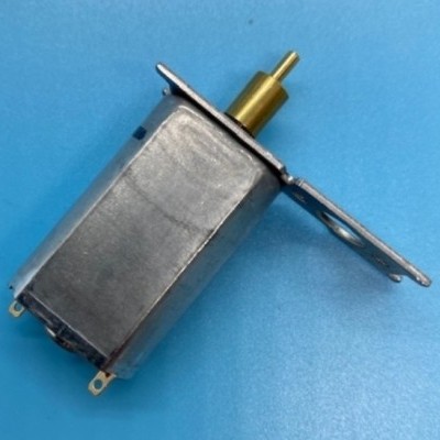 Motor elétrico pequeno metálico com eixo dourado e base metálica sobre superfície azul