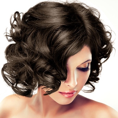 Mulher com cabelo castanho curto e encaracolado, maquilhagem azul e rosa, fundo branco