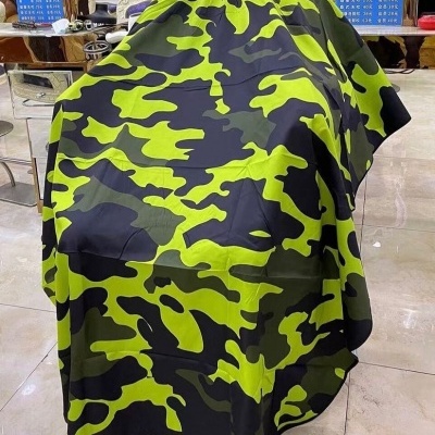 Capa de barbeiro camuflada verde, preta e cinza num salão de cabeleireiro