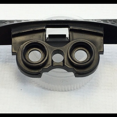 Peça preta de plástico com duas aberturas circulares sobre base branca