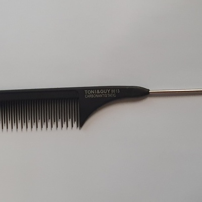 Pente fino preto com cabo metálico sobre fundo branco