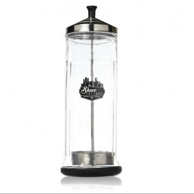 Frasco cilíndrico transparente com tampa e base metálicas e rótulo preto e branco