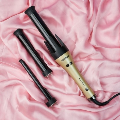 Conjunto de modelador de cabelo com três acessórios preto e dourado sobre tecido rosa