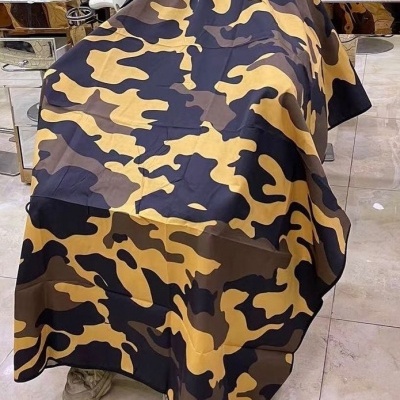 Capa de corte de cabelo camuflada com botões pretos numa cadeira de barbearia