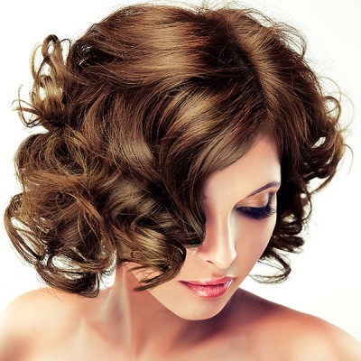 Mulher com cabelo castanho cacheado e maquilhagem suave