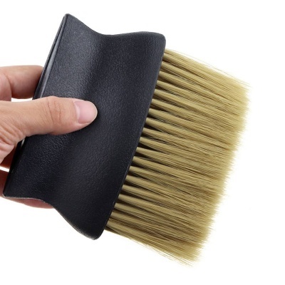 Escova com cerdas bege e cabo preto segurada por uma mão