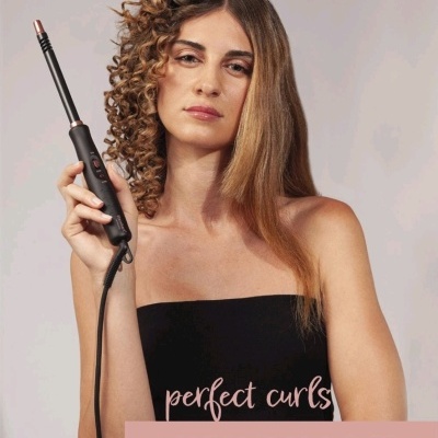 Mulher segurando modelador de cachos preto com ponta de cobre, cabelo meio liso meio encaracolado e texto promocional