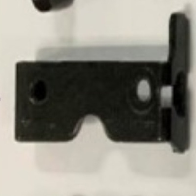 Peça metálica preta com dois furos ovais em superfície branca