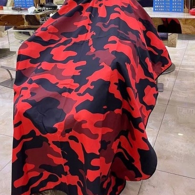 Capa de corte camuflada vermelha e preta em pessoa num cabeleireiro