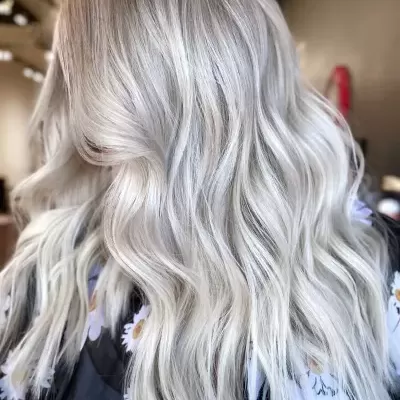 Cabelo loiro platinado ondulado e longo com camisa floral preta