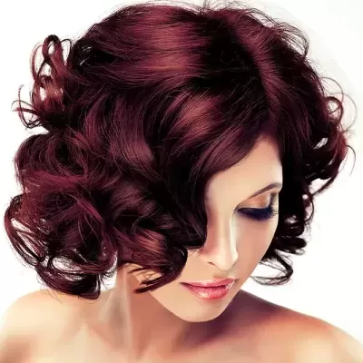 Mulher com cabelo encaracolado castanho avermelhado e maquilhagem subtil