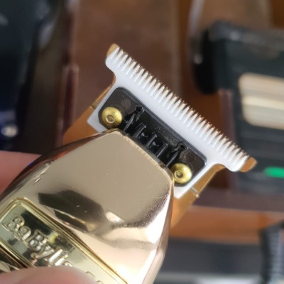 Máquina de cortar cabelo dourada com lâmina branca e texto BABILISS