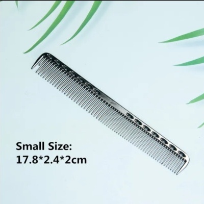 Pente prateado pequeno com padrão preto sobre fundo branco com folhas verdes