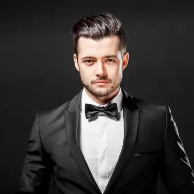 Homem de fato preto e gravata borboleta num fundo preto