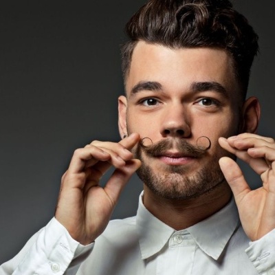 Homem com camisa branca a ajeitar o bigode encaracolado