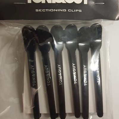 Cinco ganchos de secção pretos TONI&GUY em embalagem plástica com cartaz preto