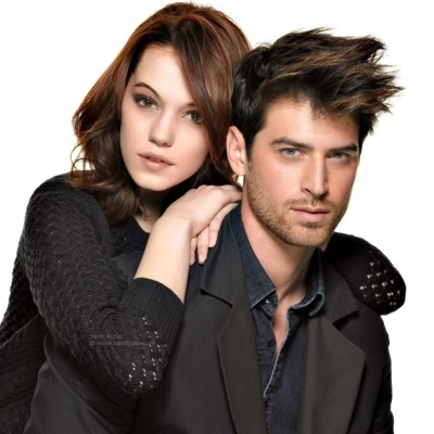 Casal jovem com roupas pretas, cabelo arranjado, fundo branco