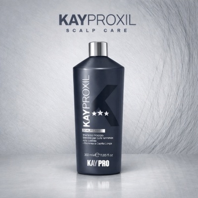 Frasco preto de champô KayPro KAYPROXIL SCALP CARE sobre superfície cinzenta