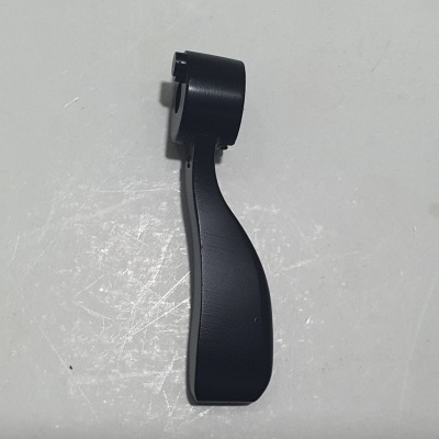 Peça de plástico preto curvo sobre superfície branca riscada
