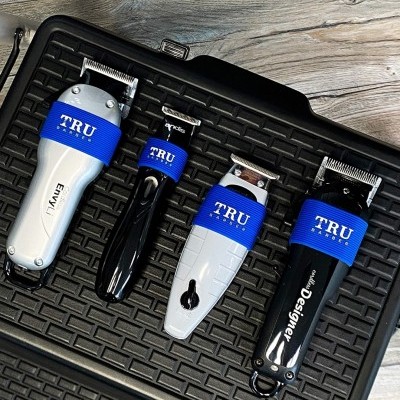 Máquinas de cortar cabelo TRU em preto e branco com detalhes azuis sobre superfície preta