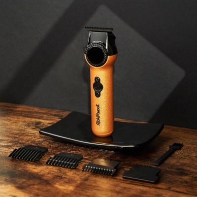 Máquina de corte cabelo preta e dourada com acessórios sobre mesa de madeira