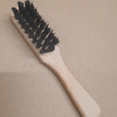 Escova de madeira com cerdas pretas sobre superfície castanha clara
