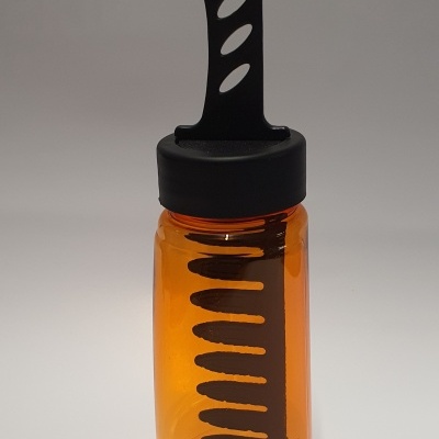 Frasco plástico âmbar com tampa preta e peça preta com recortes.