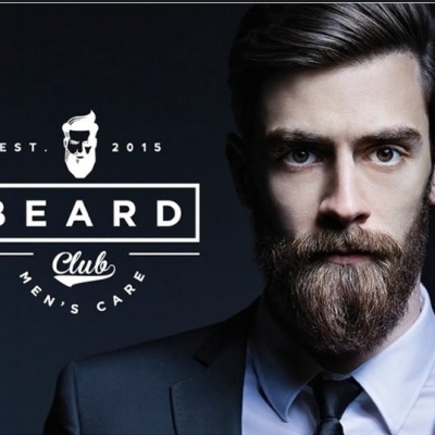 Homem com barba espessa e fato azul escuro junto ao logo BEARD Club