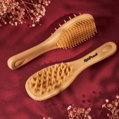 Duas escovas de cabelo cor de areia sobre tecido vermelho com flores secas