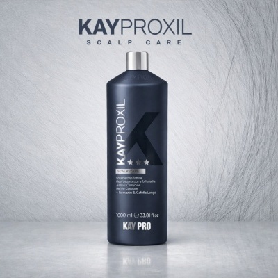 Garrafa de xampu Kayproxil Scalp Care preta sobre superfície cinzenta com fundo de cabelos finos