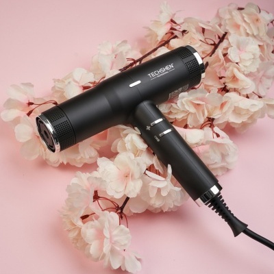 Secador de cabelo preto TECHSHEM sobre flores claras e fundo rosa