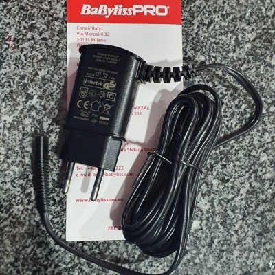 Carregador preto BaBylissPRO com ficha europeia sobre papel com logotipo vermelho e granito cinza.