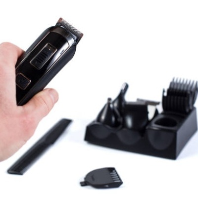 Máquina de cortar cabelo preta e acessórios sobre fundo branco