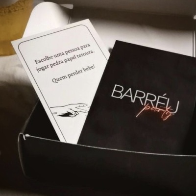 Caixa aberta com dois baralhos de cartas, preto e branco, com texto em português.