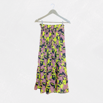 Saia longa rosa com flores amarelas e pretas pendurada num cabide branco