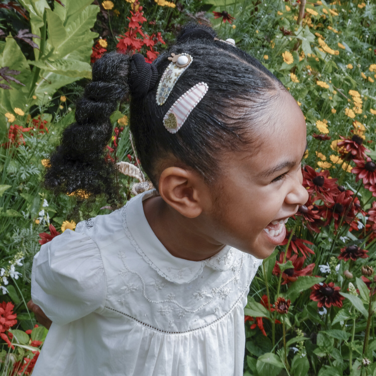 Criança com cabelo preso e ganchos decorativos em jardim florido