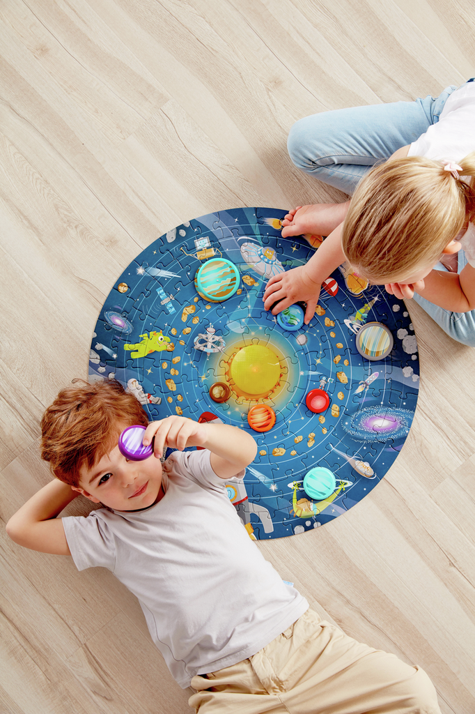 Crianças a montar puzzle do sistema solar em chão de madeira
